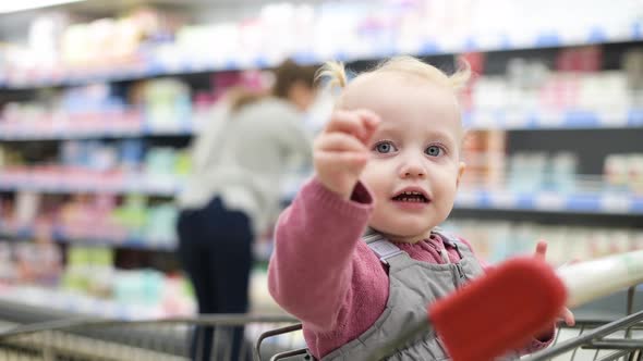 little girl sitting in a grocery cart and waiting for mom