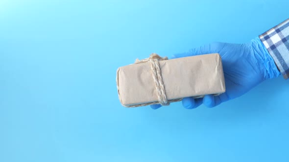 Male Hand in a Blue Medical Glove Gives a Gift