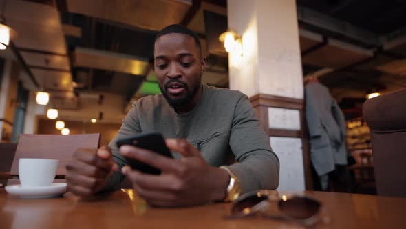 African American Man Online Chatting in a Cafe