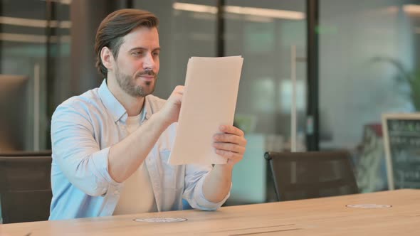 Mature Adult Man Celebrating Success While Reading Documents