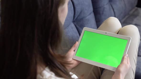A Girl is Holding a Tablet with a Green Screen