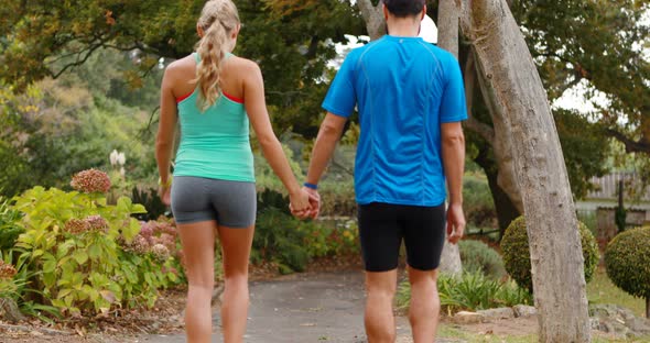 Rear view of couple holding hands while walking