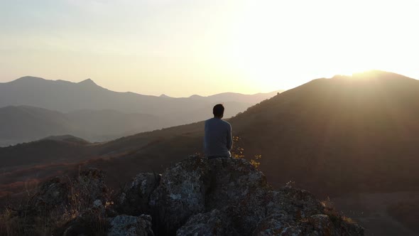 CONCEPT OF INSIGHTING Sun Rays Pass Through the Head of a Person Who Sits on Top of a Mountain and