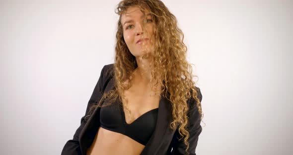 Portrait of a Smiling Curly-haired Girl Who Is in the Studio on a White Background, Wearing a Black