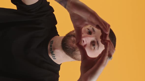 Vertical Clip of a Caucasian Middleaged Guy in a Black Tee Showing Heart Sign Gesture to the Camera