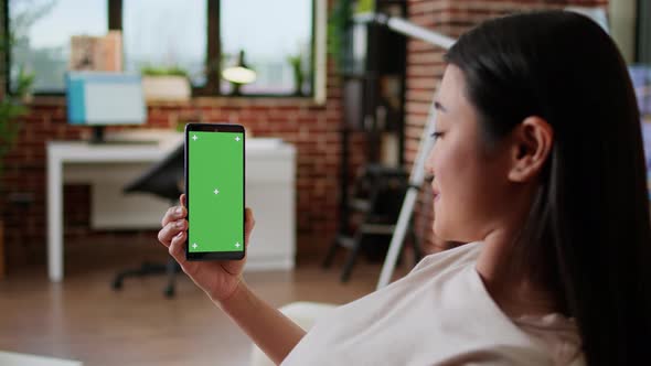 Cheerful Person Sitting on Couch with Mobile Cellphone Having Chroma Key Mockup Display Background