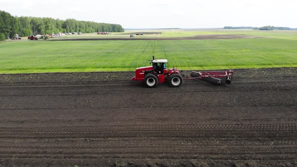 Red Harvester Drives Across Field and Plows Earth