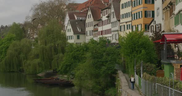 Tourist walking along path overlooking river as birds fly near in downtown Tubingen historic distric