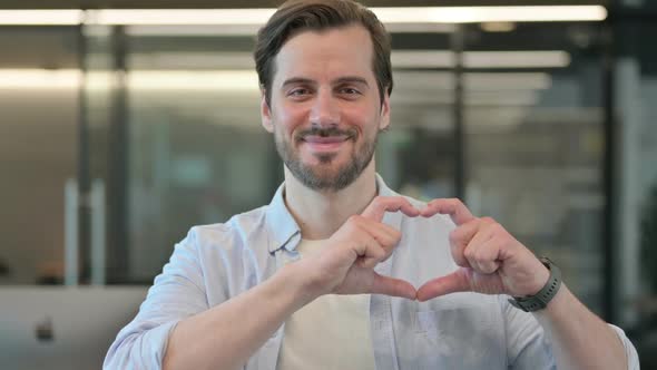 Portrait of Mature Adult Man Showing Heart Sign By Hand