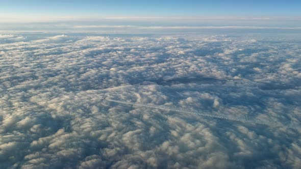 Incredible view from the cockpit of an airplane flying high above the clouds leaving a long white co