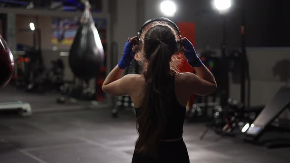 Fit Female Boxer Walks By Boxing Gym in Headphones Warming Up