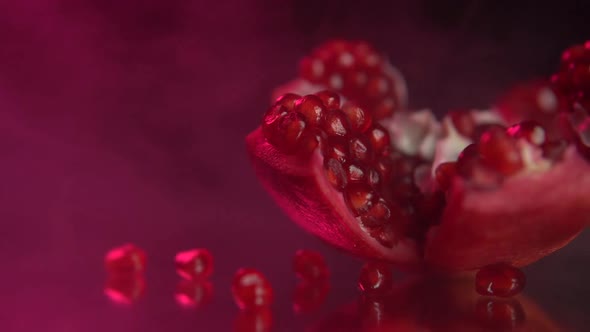 Pomegranate opened fruit, fresh, red, ripe garnet seeds on a black background with smoke.