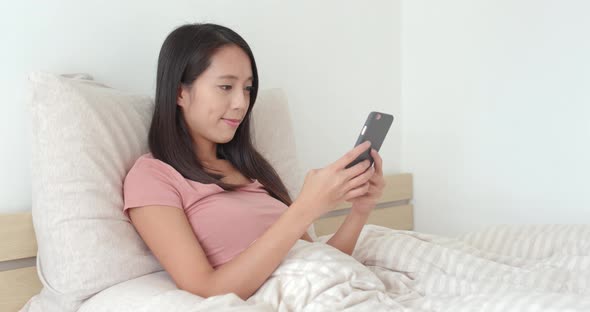 Woman using mobile phone on bed
