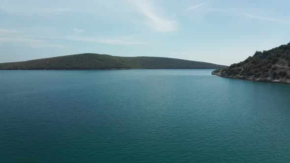 Super wide panorama shot of a beautiful calm ocean in Croatia. Drone flies forward. Small green hill