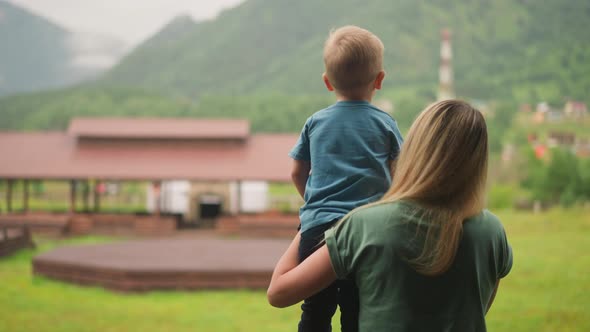Woman Holds Little Son Showing Distant Mountains in Hotel