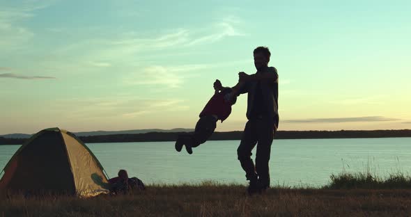 Father Twists His Son in His Arms in Nature
