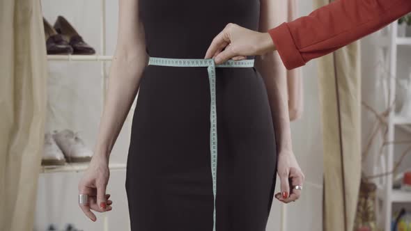 Front View of Unrecognizable Slim Caucasian Woman in Elegant Black Dress Standing in Atelier with