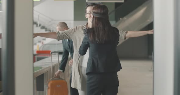 Back View of Airport Employee Examining Mid-adult Caucasian Woman in Eyeglasses at Security Gates As