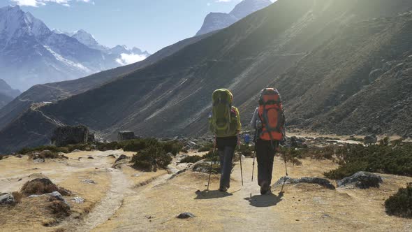 Two Women with Backpacks Are Walking Along the Path in Nepal Mountains. Slow Motion Shot. , FHD