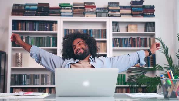 Joyful Arabian Man Freelancer Leans Back on Split of Chair After Office Work