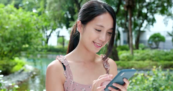 Woman Use of Mobile Phone Online in The Park