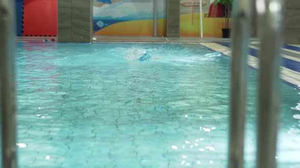 Little Caucasian Boy Wearing Goggles Swimming in a Pool and Getting Out From Water