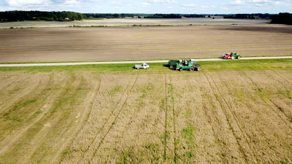 Aerial view of a green vintage combine harvester mows wheat in the field for the food industry, yell