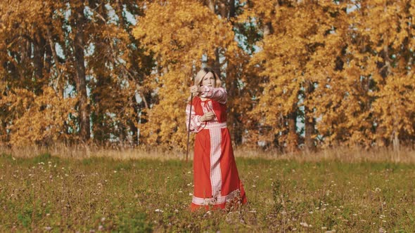 Feisty Woman in Red National Dress Rotating a Sword Around Herself and Throwing It Up