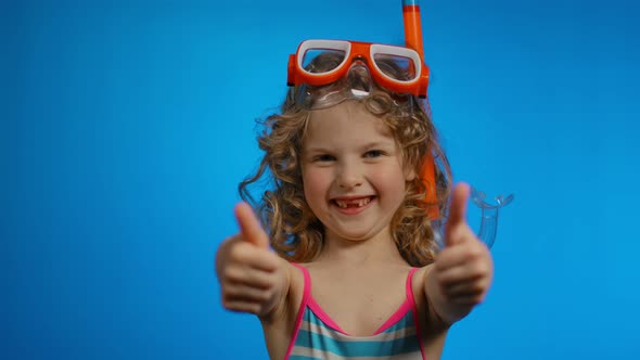 Little Curly Girl with Swimming Mask and Snorkel is Showing Two Big Thumbs