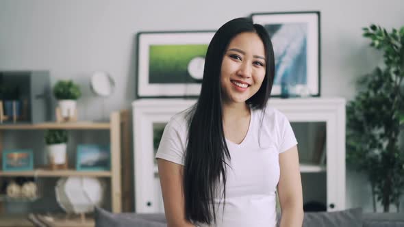 Slow Motion Portrait of Beautiful Asian Woman with Long Hair Standing in Modern Apartment, Smiling