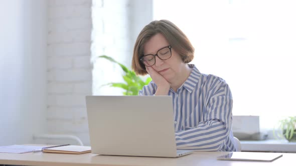 Senior Woman Sleeping While Sitting in Office with Laptop