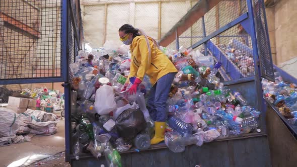 Footage of a Young Woman in Yellow Jacket and Gloves Scoops Used Bottles By Hands Used Plastic