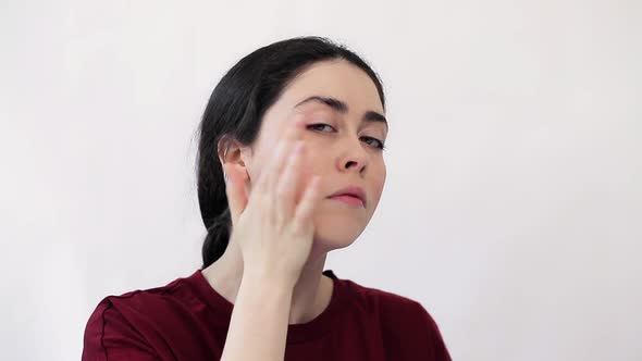 Portrait of a sad young woman masking redness on her cheeks with makeup