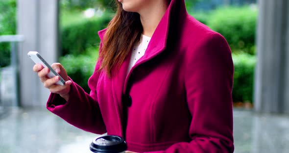 Businesswoman using mobile phone while having coffee