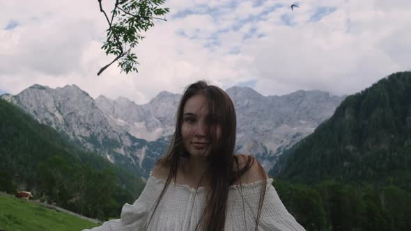 Portrait of Young Smiling Woman in Alps Mountains Background