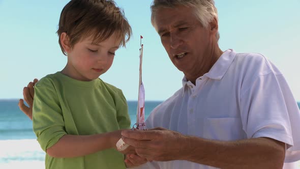 MS OF A GRANDFATHER AND GRANDSON PLAYING WITH A TOY BOAT