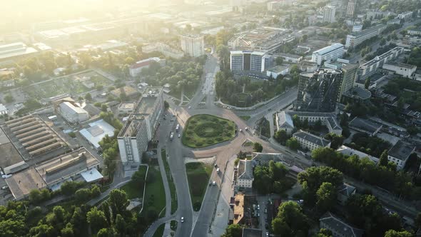 Aerial drone view of Chisinau at sunrise. Multiple buildings, trees, park, road with cars. Moldova
