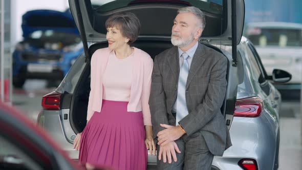 Positive Loving Senior Couple Sitting in Car Trunk Talking