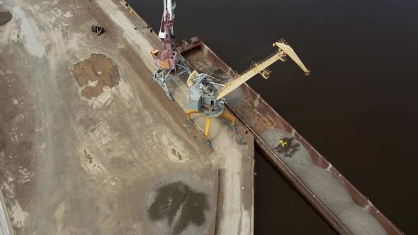 Large Harbor Cranes Onshore at the Quay Unload a River Gravel Barge Onto a Large Pile