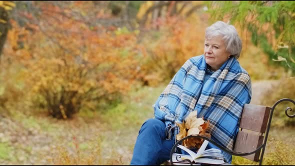 Elderly Woman Walks in the Park in Autumn and Relaxes.
