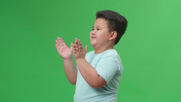 Side View Of Asian Little Boy Clapping Her Hands In The Green Screen Studio alt