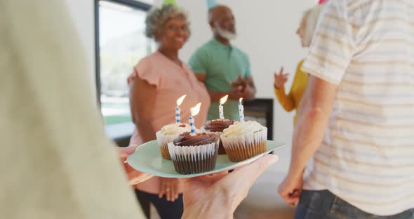 Happy senior diverse people at birthday party with cake at retirement home