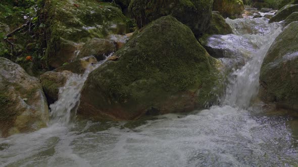 Close up slow motion of splashing little waterfall in wild nature of Switzerland - 4k Pan shot in gr