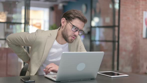 Young Man with Laptop Having Back Pain