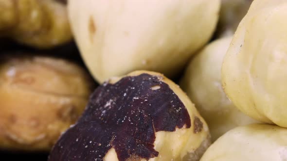 Macro shot of a trail mix: hazelnuts, almonds, walnuts rotating over a black surface.