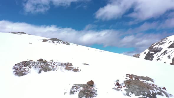 Aerial dolly in flying over snow covered peak at Hielo Azul Hill, mountains in background, El Bolsón