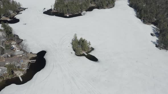 Drone shot flying to the left and panning right, around a little house on an island, with a frozen l