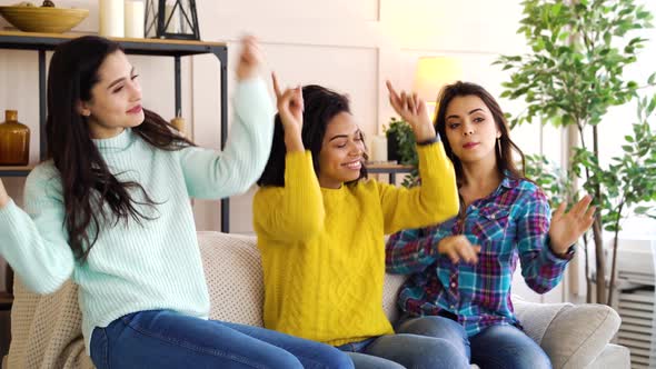 Happy girls dancing on sofa at home