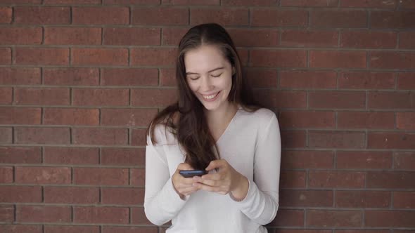 Happy woman typing on the phone and smiling, slow motion