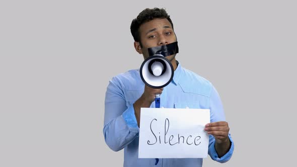 Darkskinned Man Speaking in Megaphone with Taped Mouth